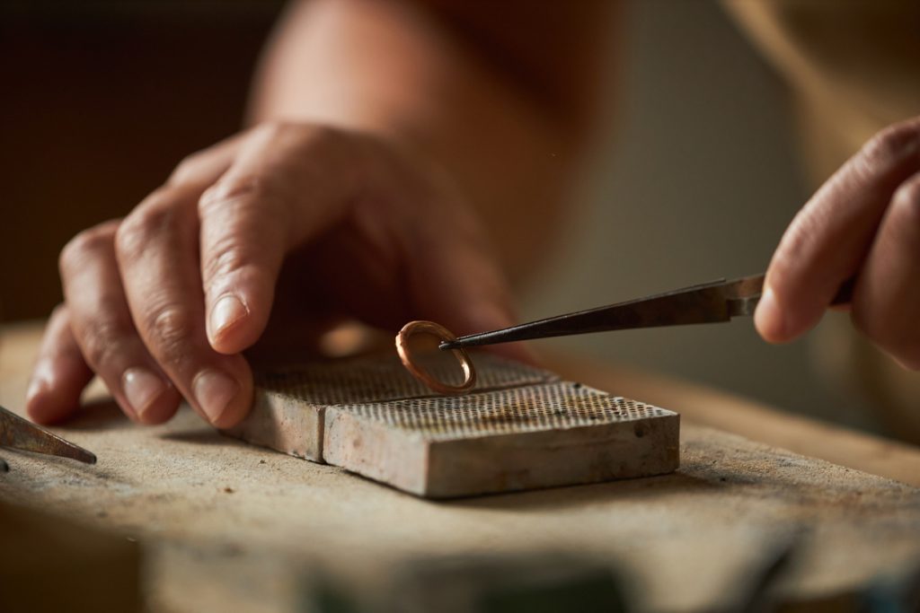 Close up of artisan jeweler holding handmade ring.
