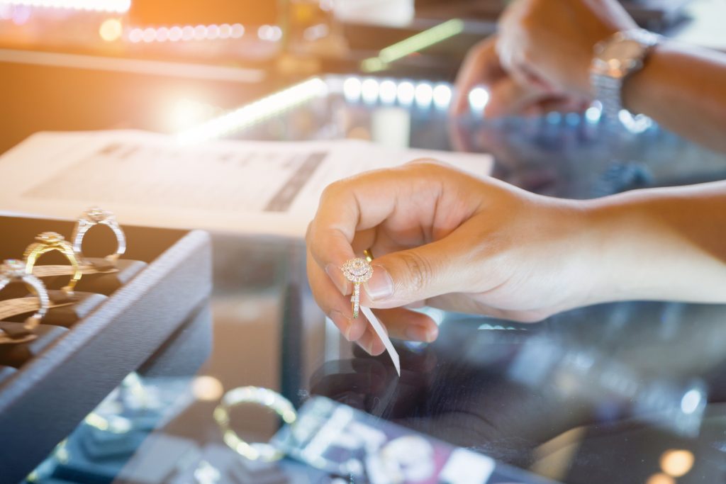 A hand of a woman choosing wedding rings at a jewelry diamond store shop.